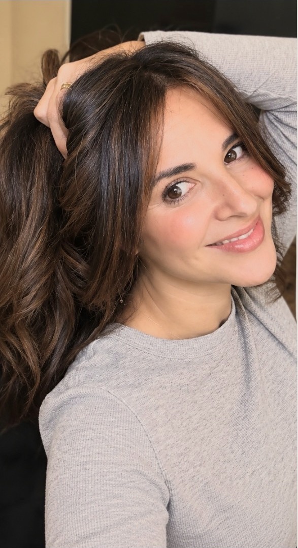Caro Manzano con camisa gris, sonriendo de forma natural y luminosa