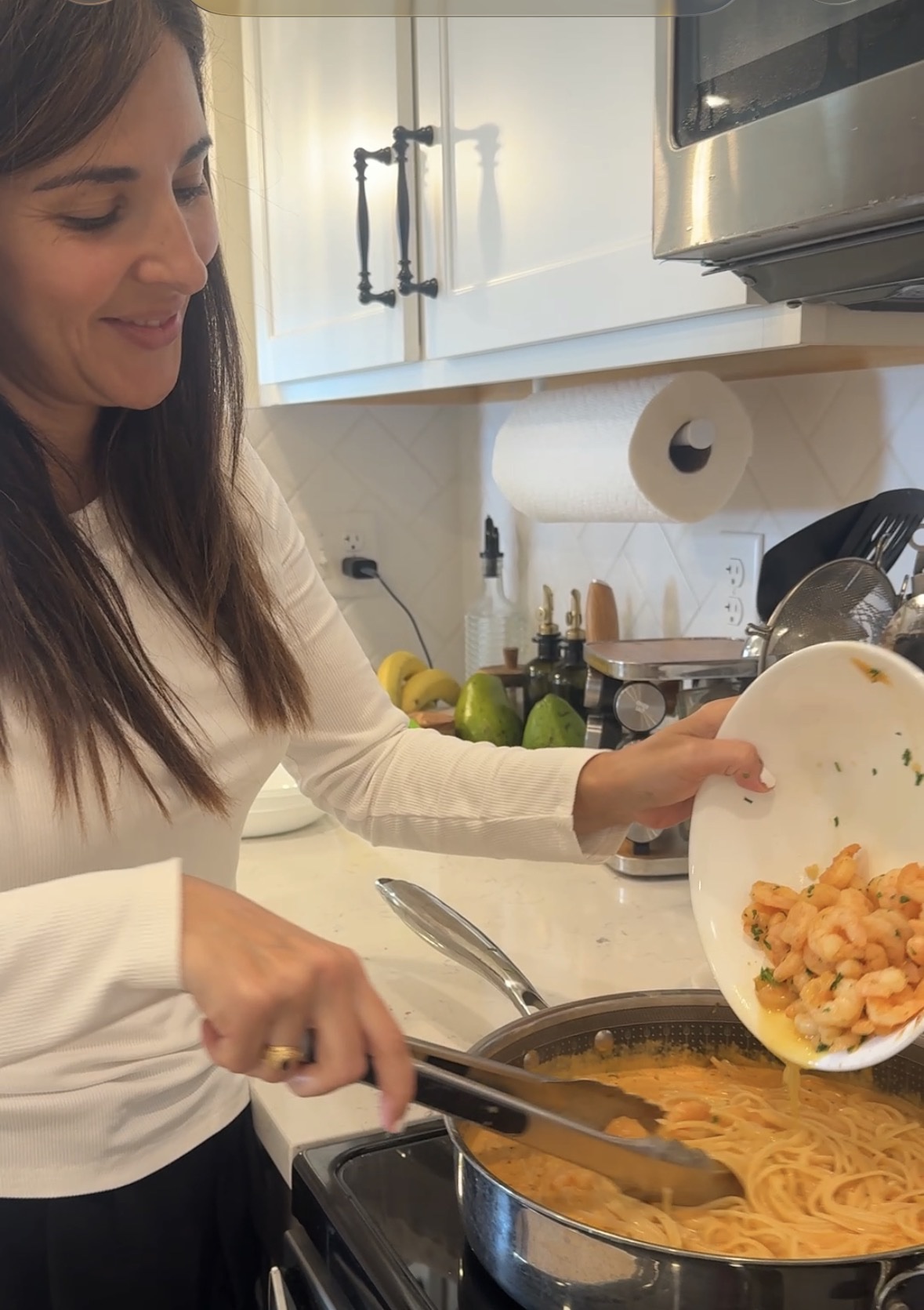 Caro agregando los camarones a la pasta cremosa en la sartén